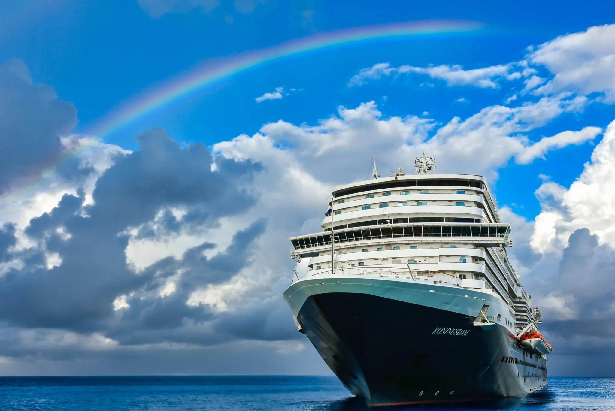 Cruise ship beneath a rainbow on the open sea