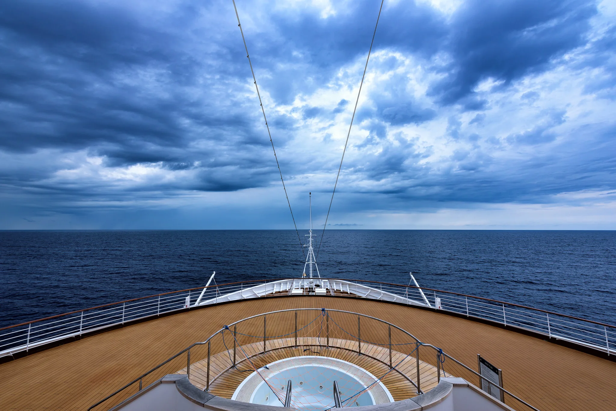 View over the bow of a vessel moving beneath dramatic clouds