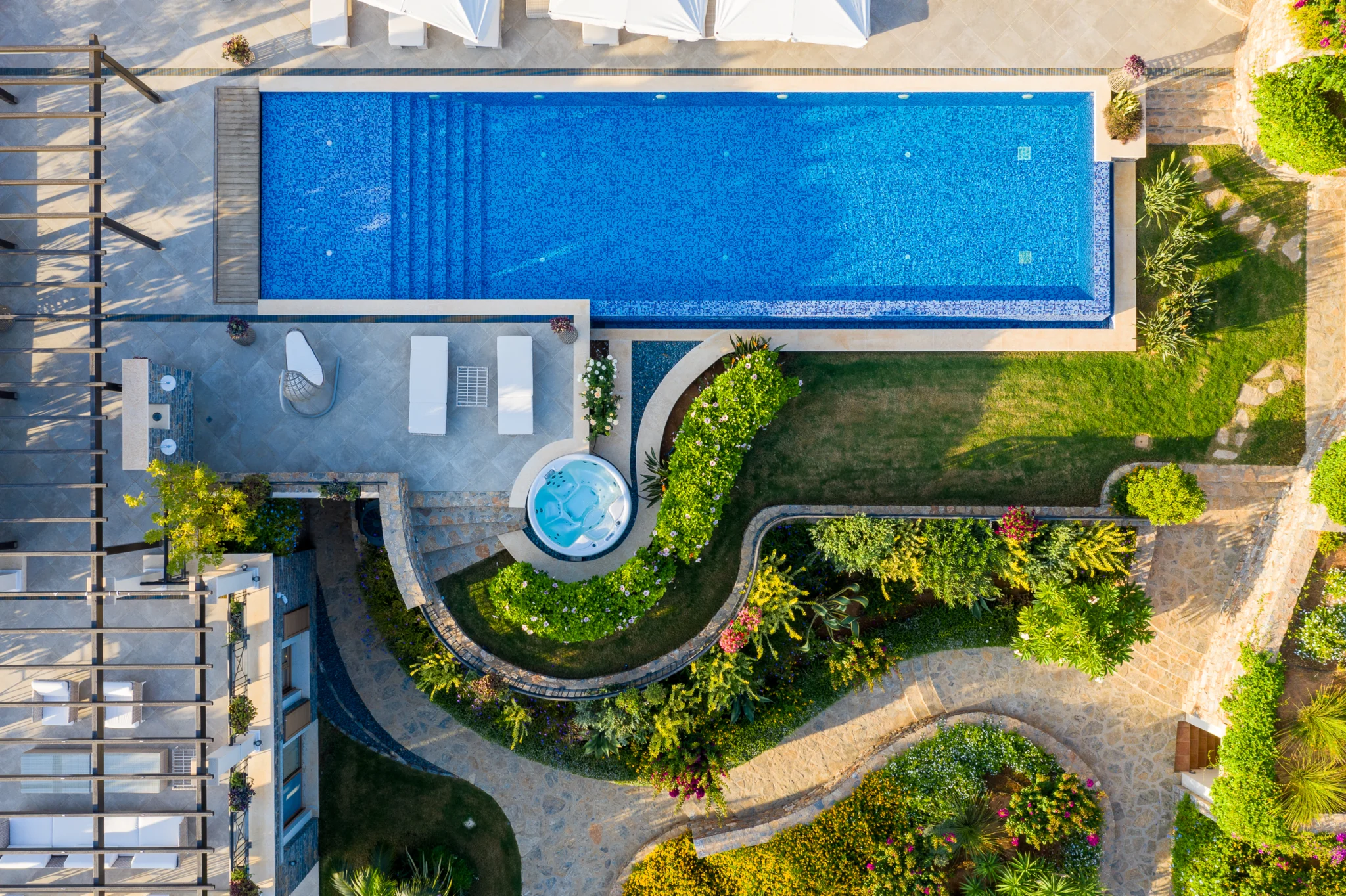 Aerial view of a swimming pool, pergola and curved garden paths at Mirum Villas, Crete, Greece
