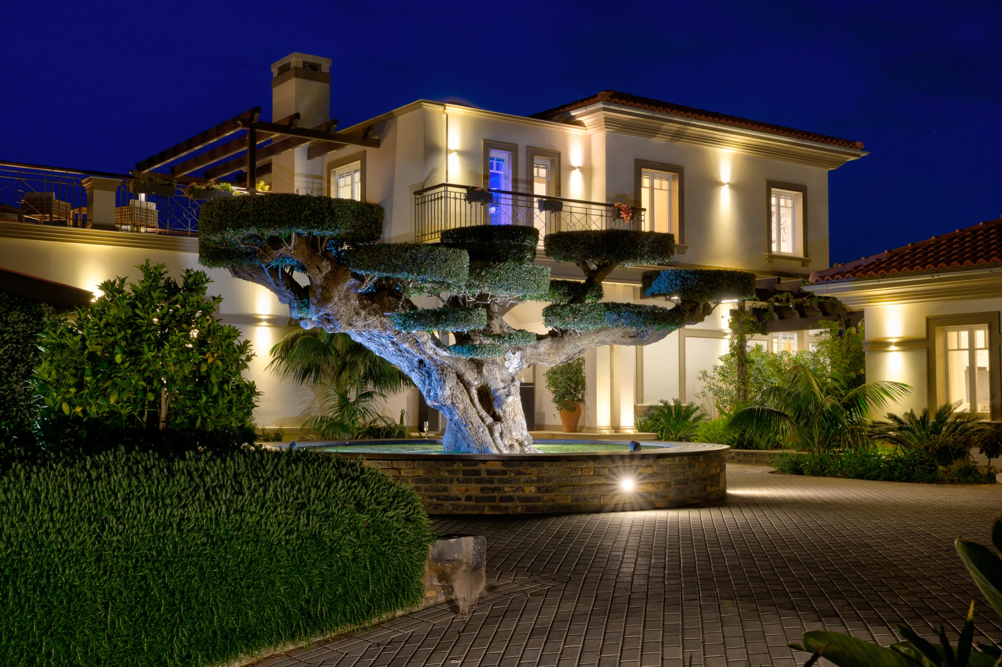 Illuminated white villa and sculpted garden trees at night at Mirum Villas, Crete, Greece
