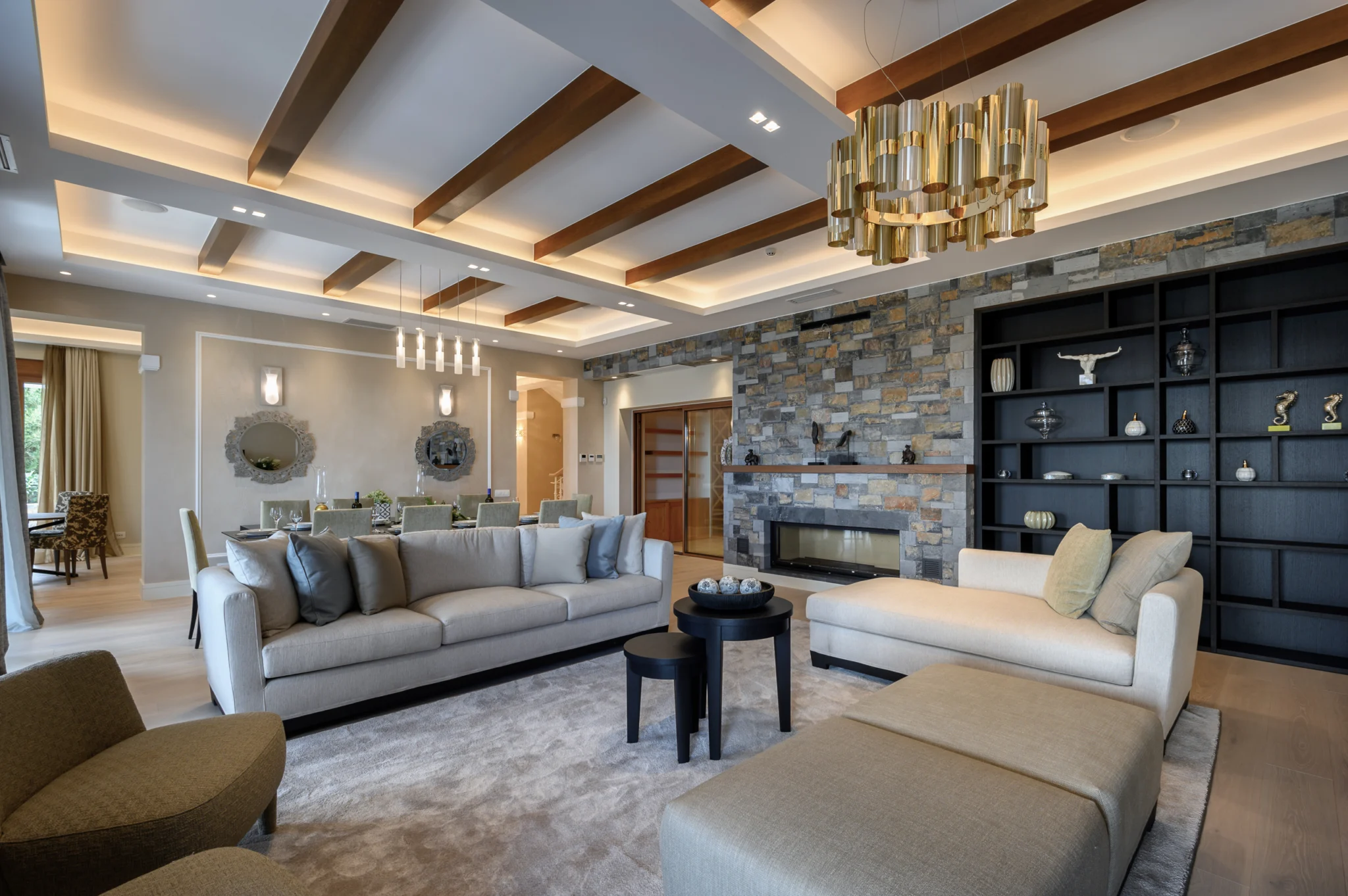 Living room with a stone fireplace, timber ceiling and bookcase at Mirum Villas, Crete, Greece