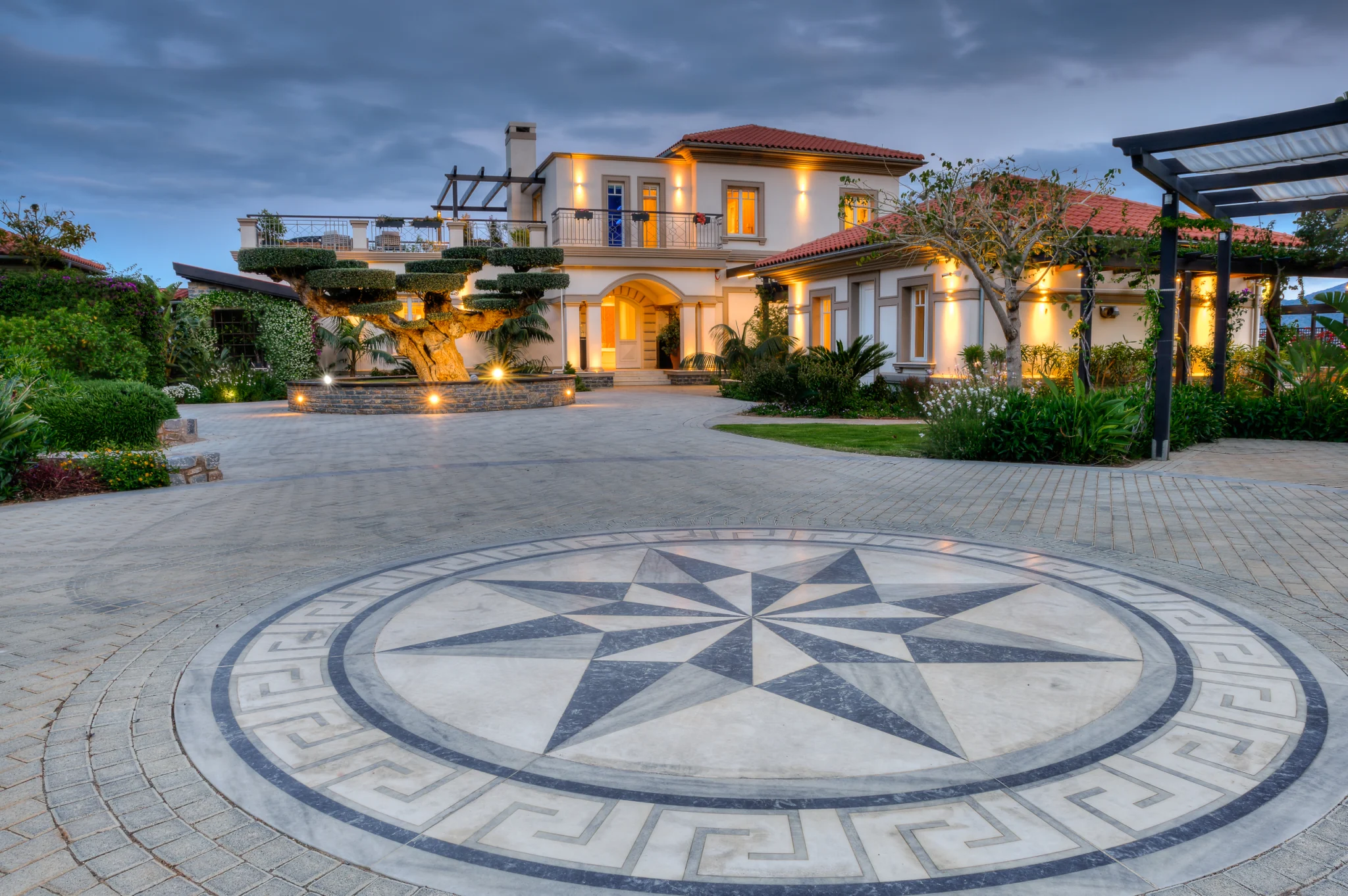 Villa entrance and compass mosaic on the driveway at dusk at Mirum Villas, Crete, Greece