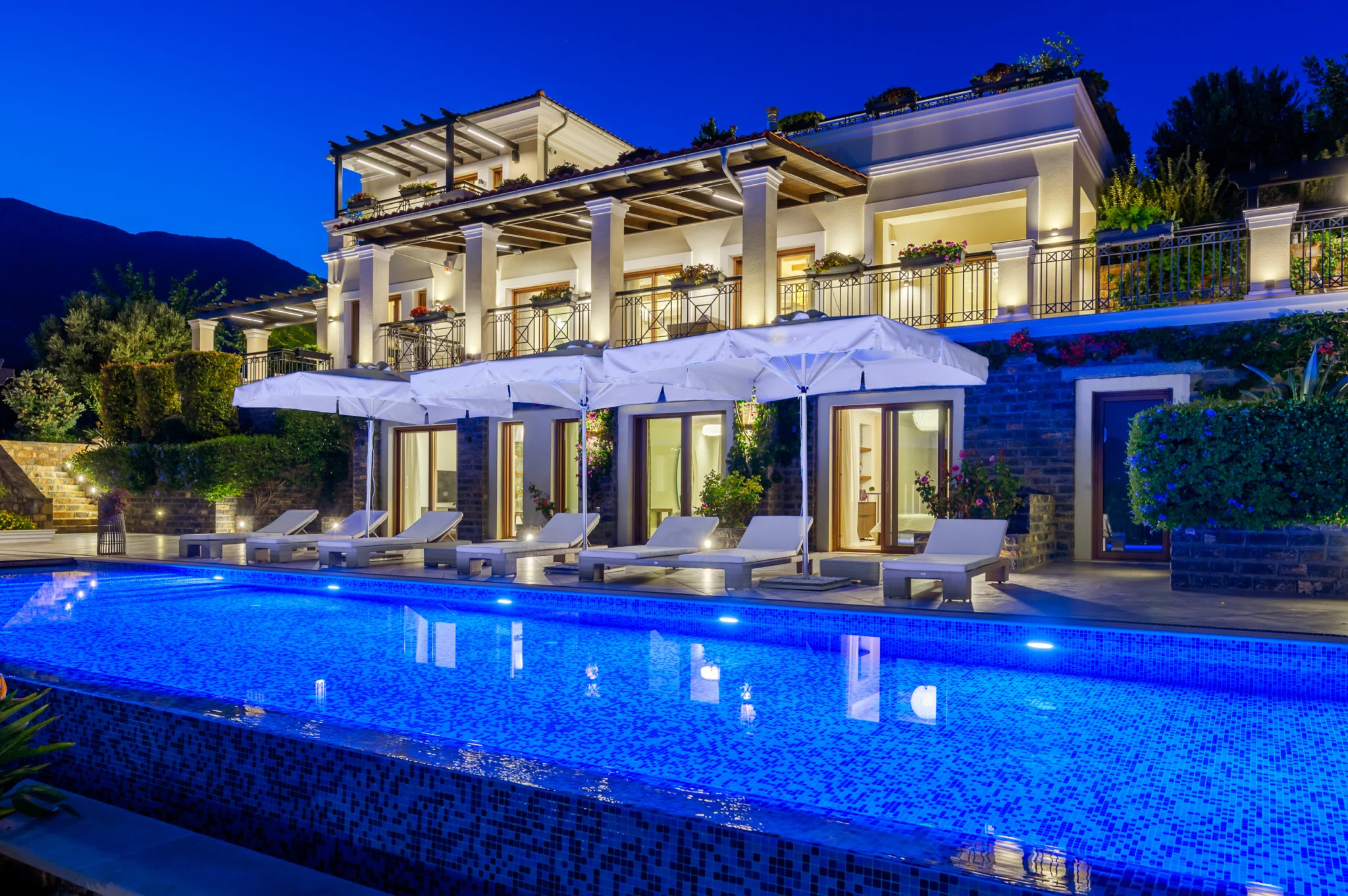 Illuminated white villa and swimming pool at blue hour at Mirum Villas, Crete, Greece