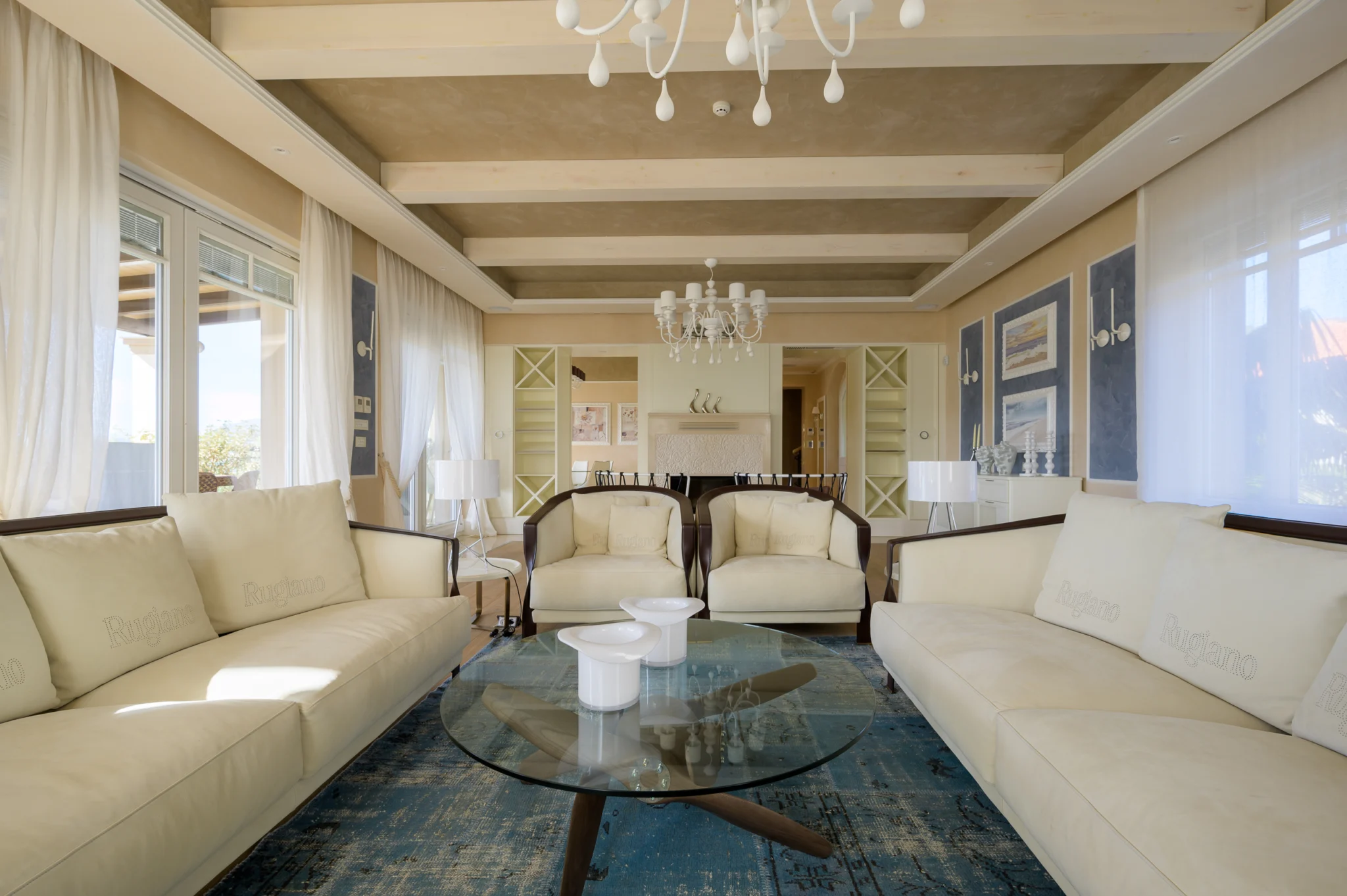 White sofas and glass coffee tables in an open living and dining room at Mirum Villas, Crete, Greece