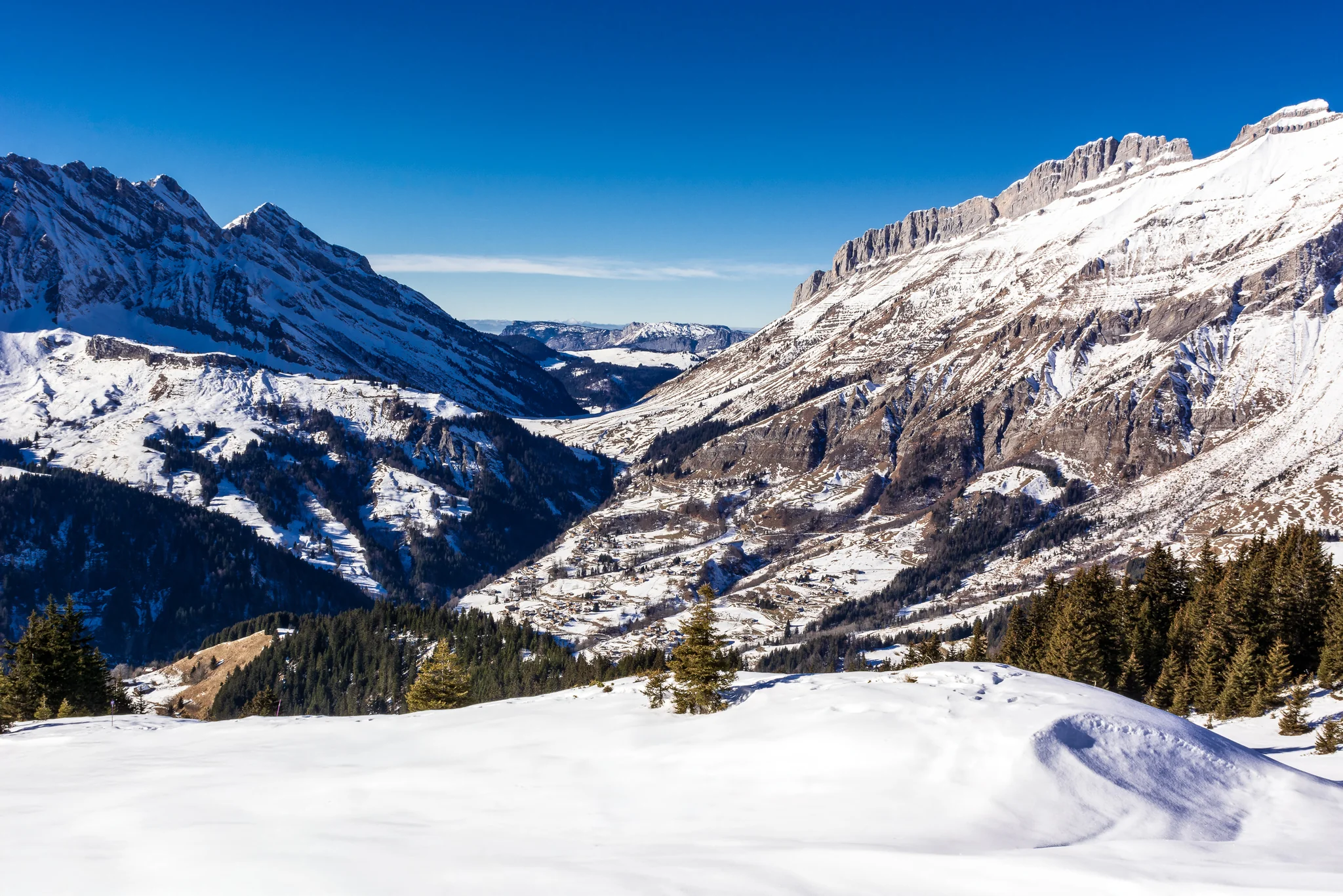 Panoramic snow-covered alpine valley surrounded by mountain ridges