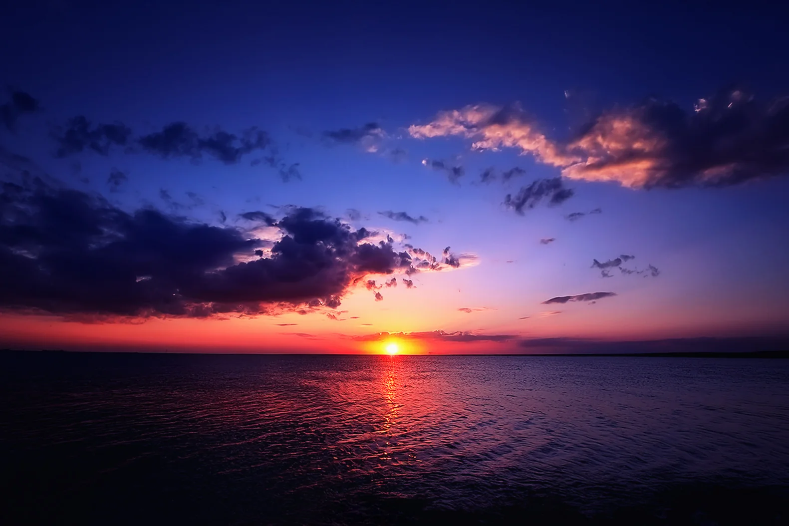 Purple and red sunset reflected across calm open water