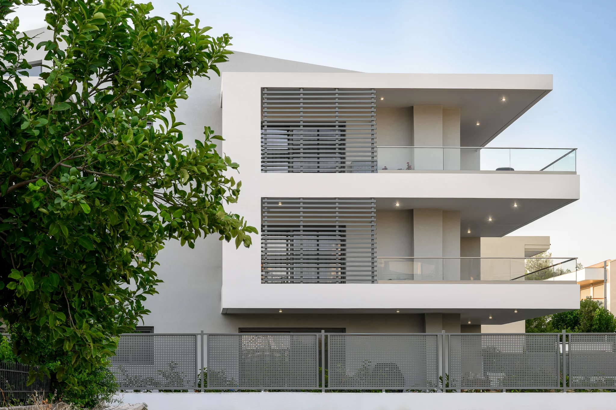 White residential facade with glass balconies and horizontal screens at Residential Complex in Athens, Athens, Attica, Greece.