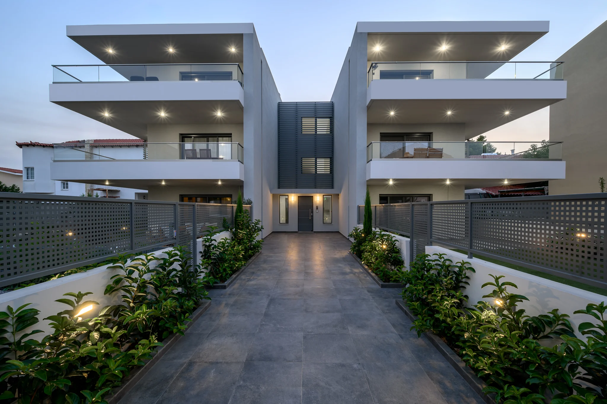 Central paved entrance and glass balconies at dusk at Residential Complex in Athens, Athens, Attica, Greece.