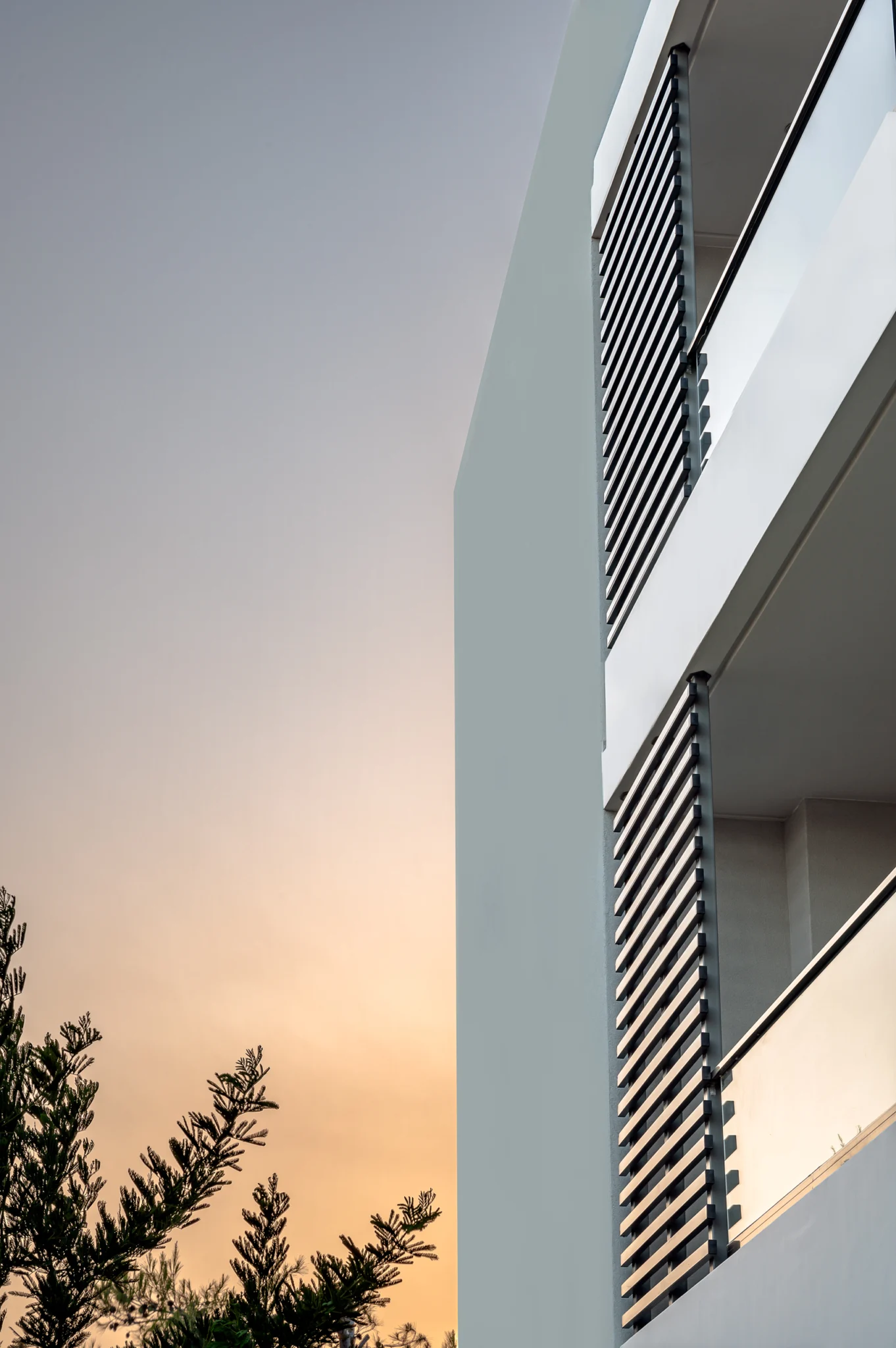 Vertical view of the facade and screening against a sunset sky at Residential Complex in Athens, Athens, Attica, Greece.
