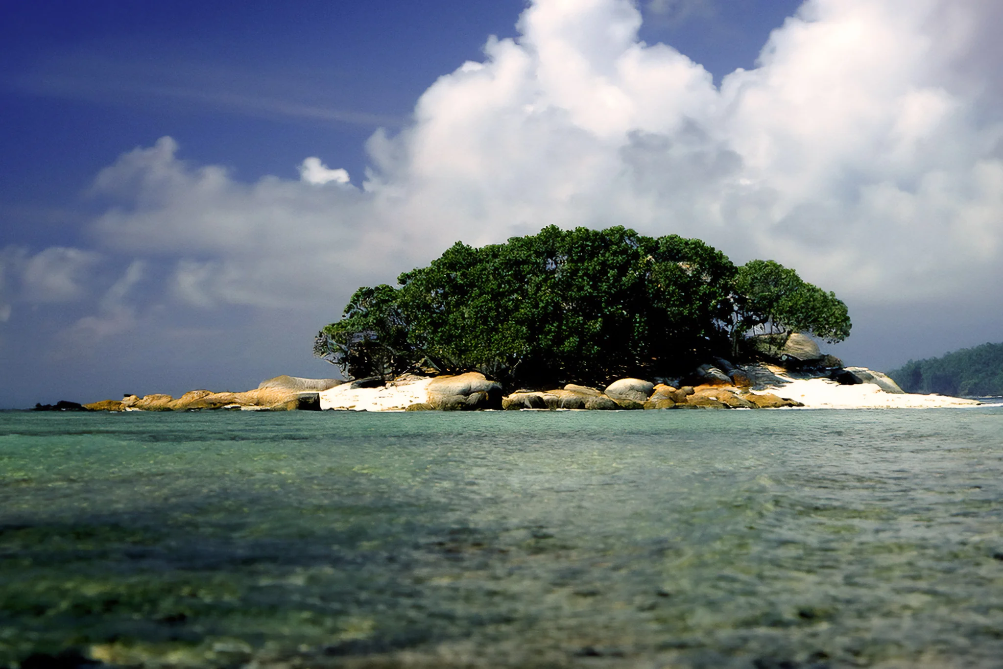 Tropical Islet in the Cook Islands Small tropical islet in shallow water beneath storm clouds in the Cook Islands