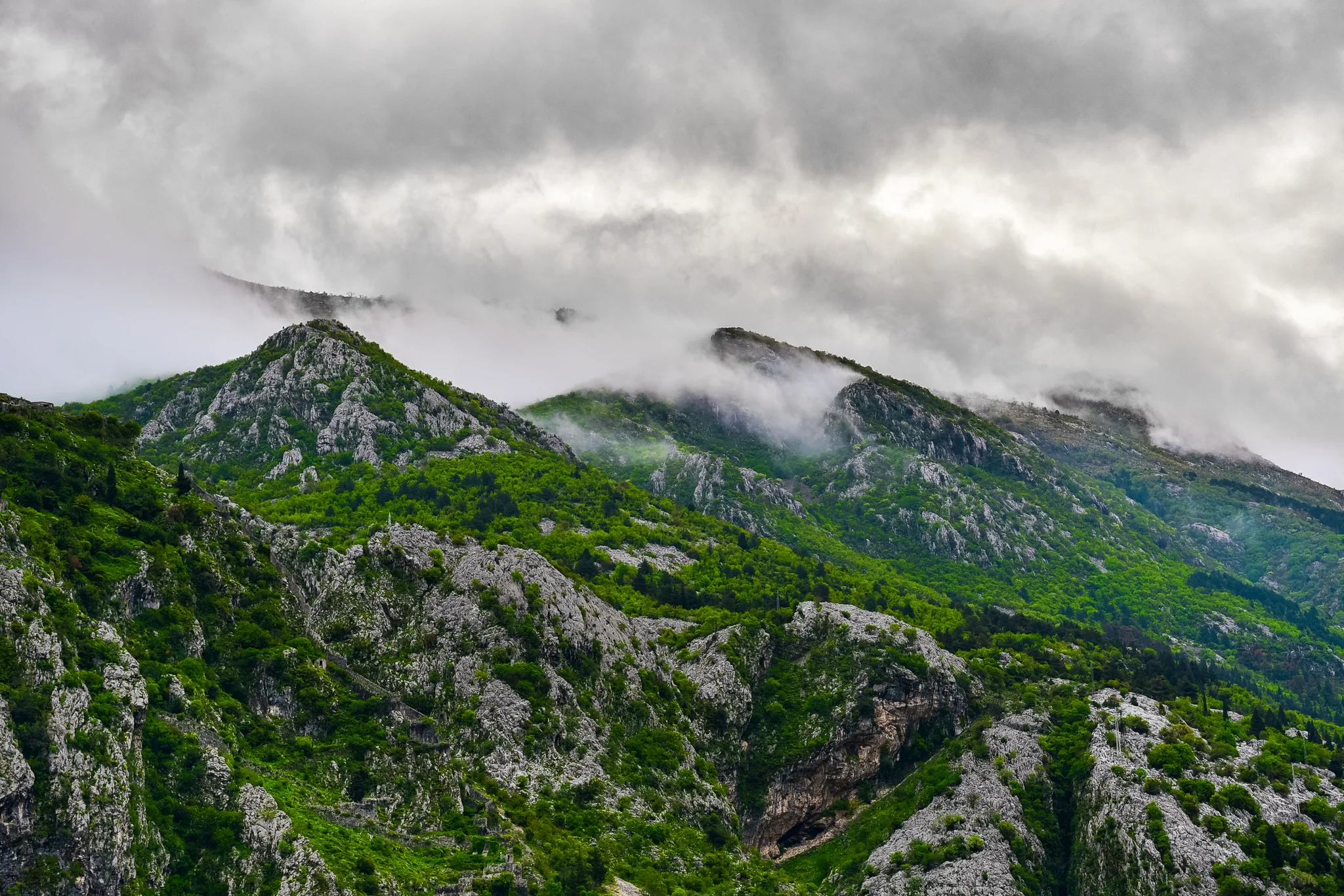 Low fog drifting across a steep green mountain ridge