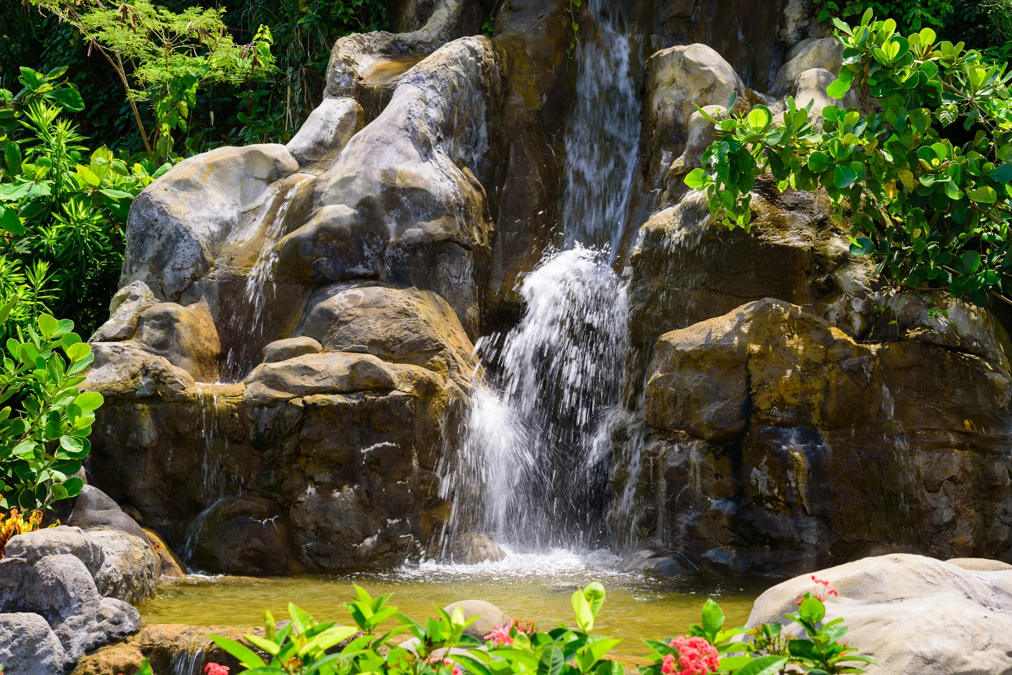Small rock waterfall surrounded by dense tropical garden foliage