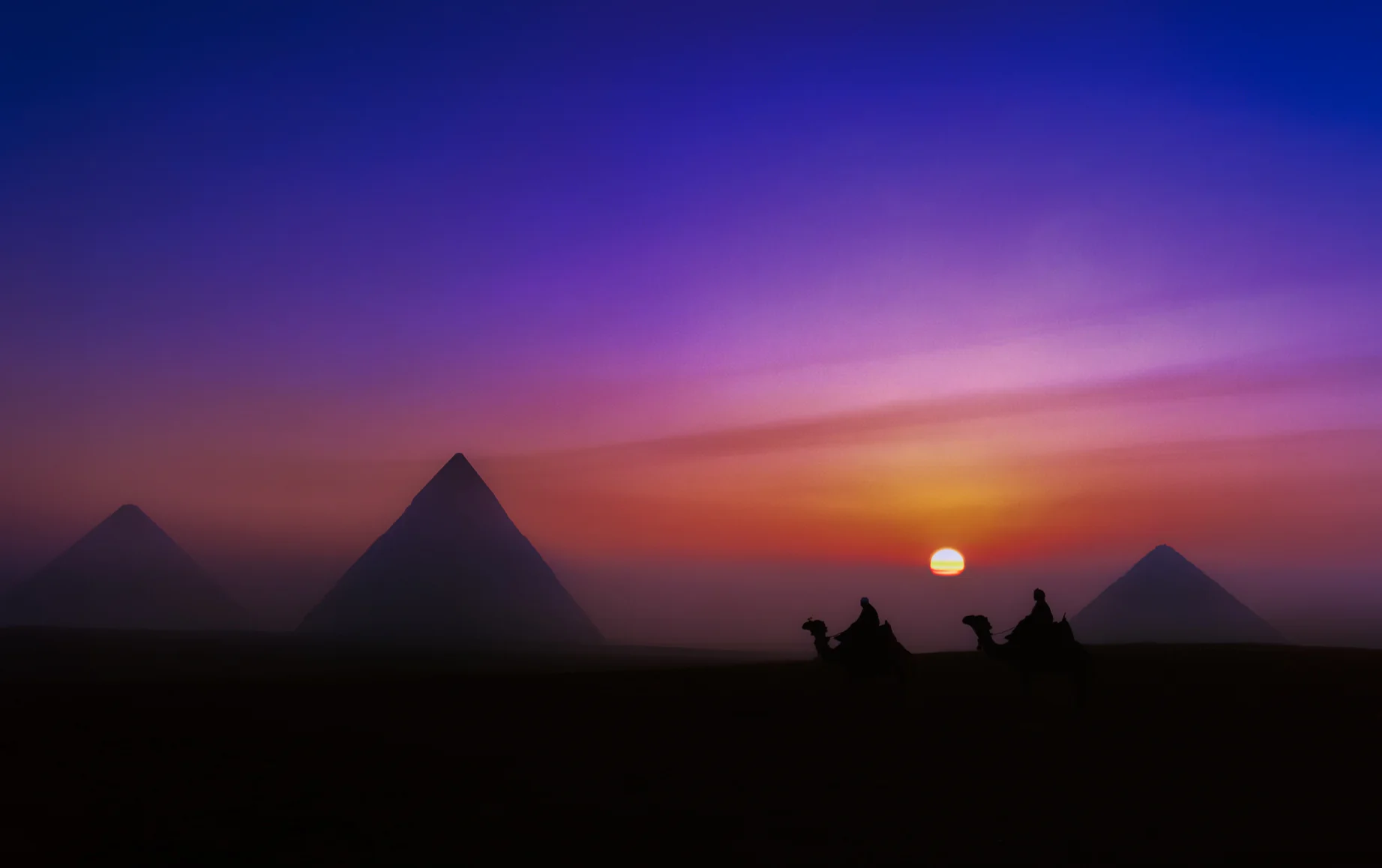 Pyramids of Giza at Sunset, Egypt Pyramids of Giza silhouetted at sunset with camel riders in Egypt