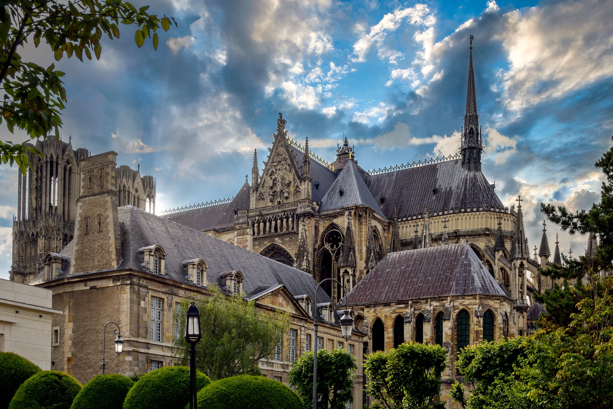 Gothic cathedral seen from a garden beneath textured clouds