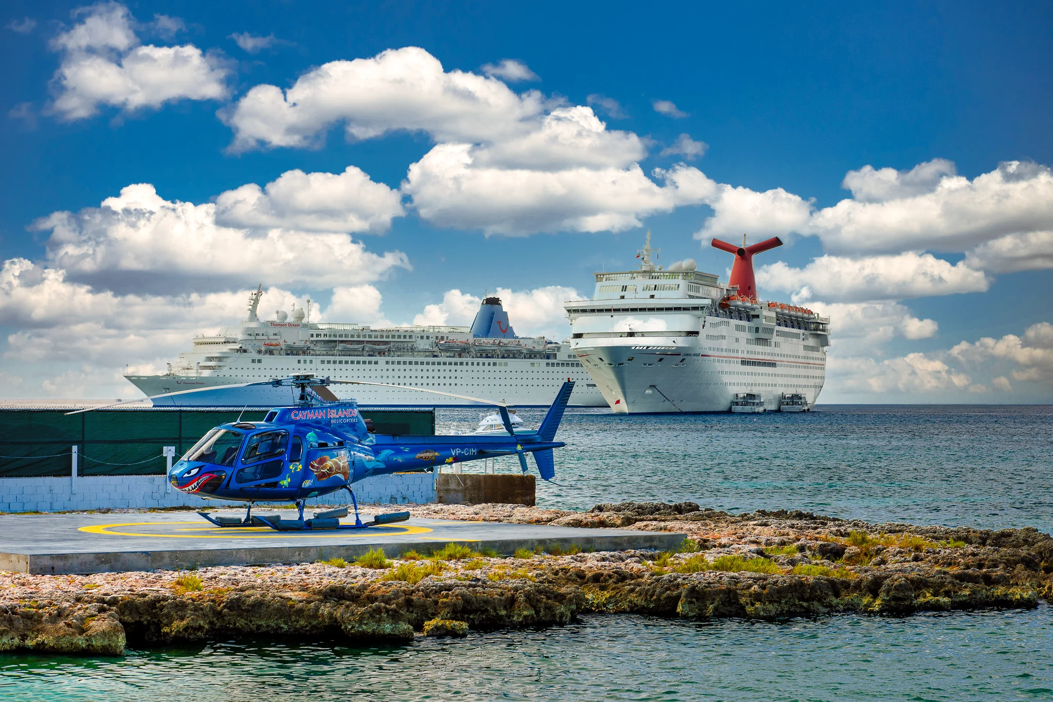 Helicopter and Cruise Ship at a Coastal Port Blue helicopter on a coastal landing pad with cruise ships beyond