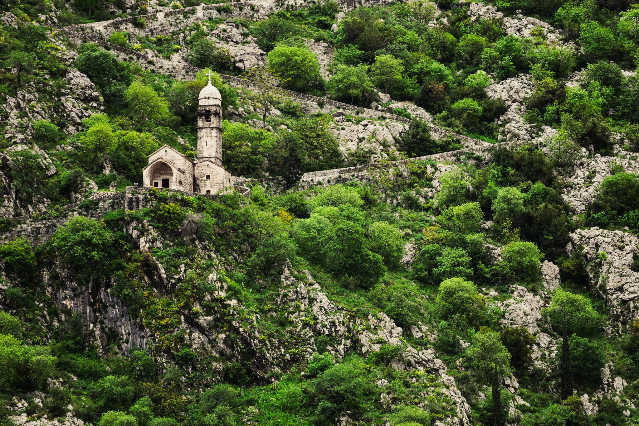 Small stone chapel set into a steep green mountainside