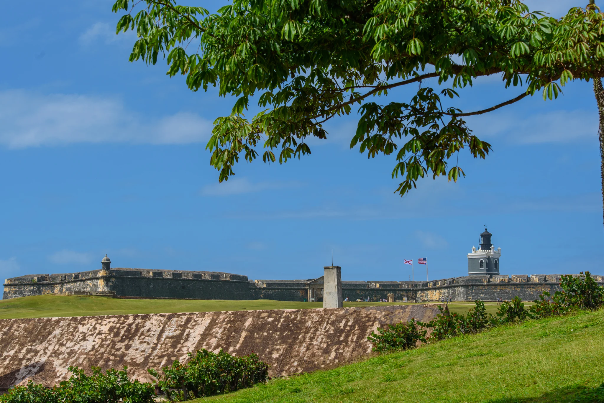 Long stone coastal fort with a small lighthouse beneath a blue sky