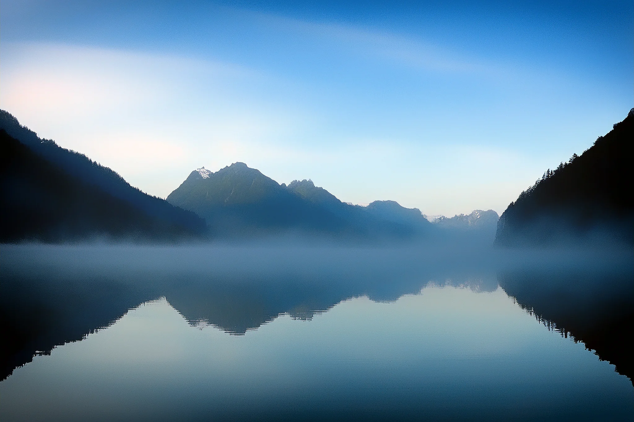 Mountain silhouettes and mist reflected in Lake Gunn, New Zealand