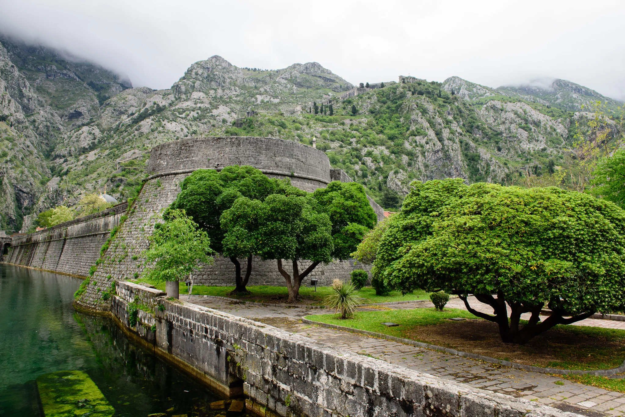 Old stone bridge crossing a green river gorge beneath misty mountains