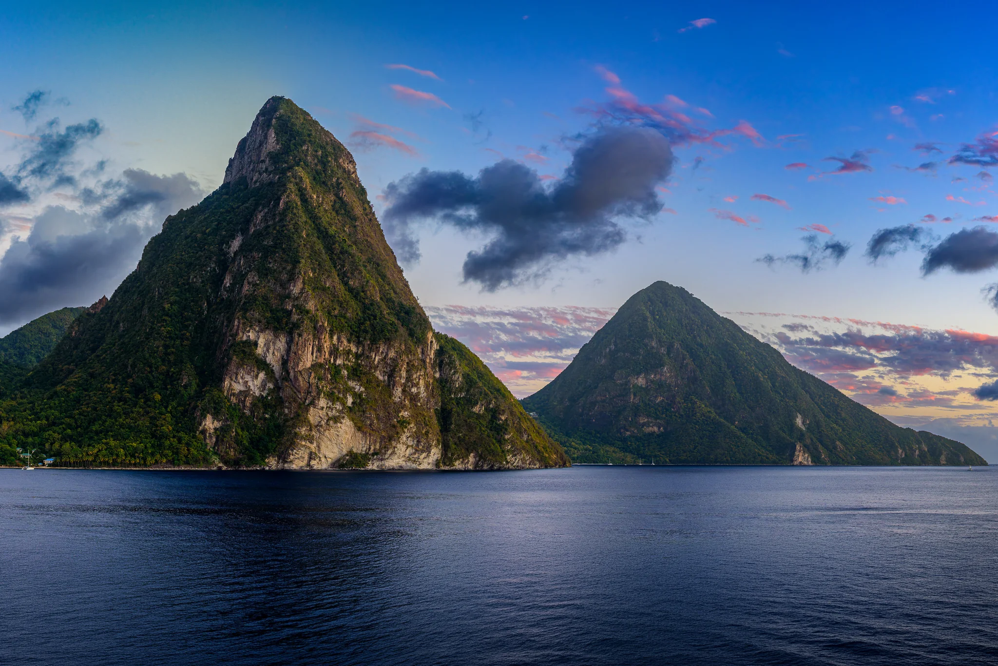 Two steep volcanic peaks rising from the sea beneath evening clouds