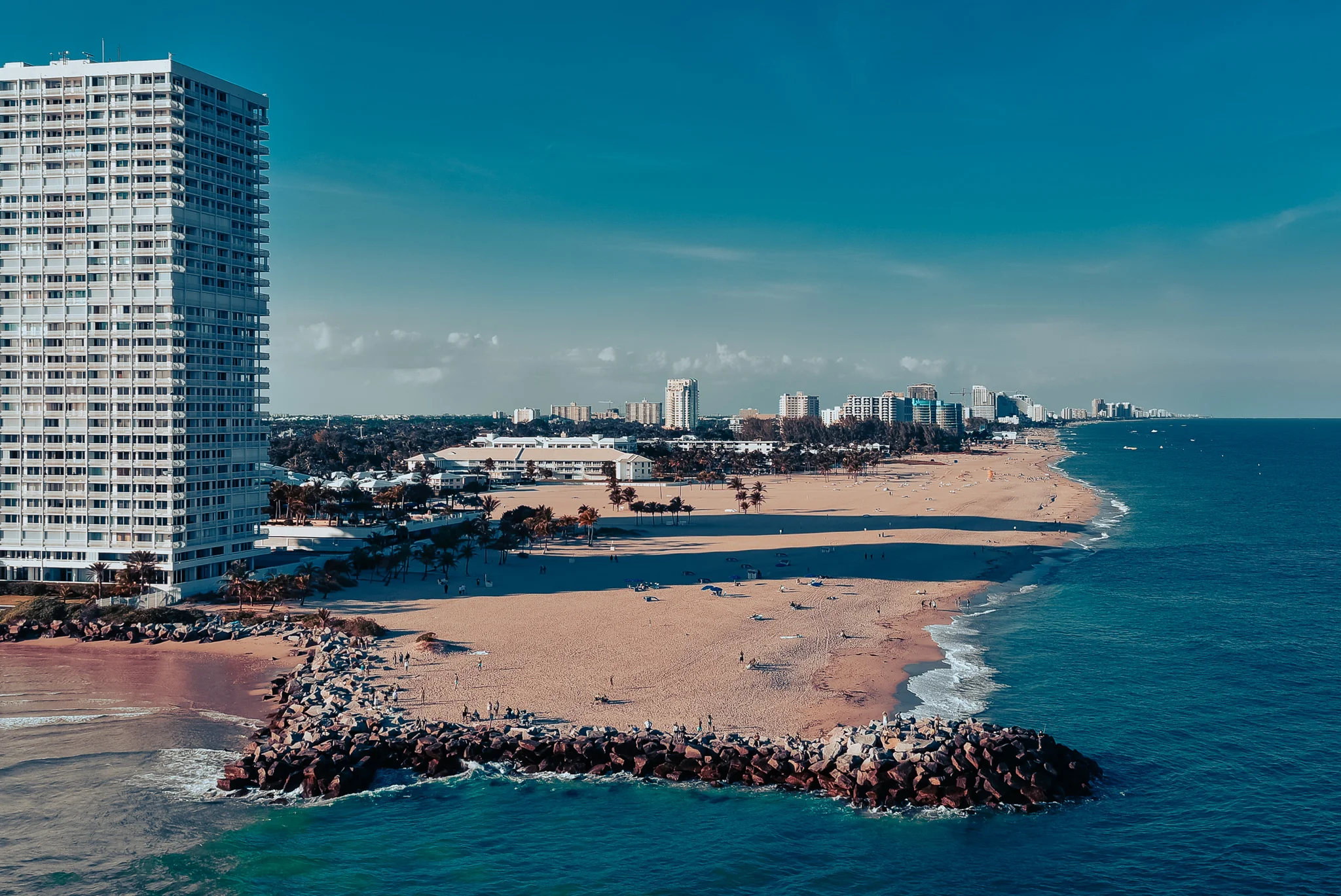 Aerial view of a city beach, breakwaters and a tall waterfront tower