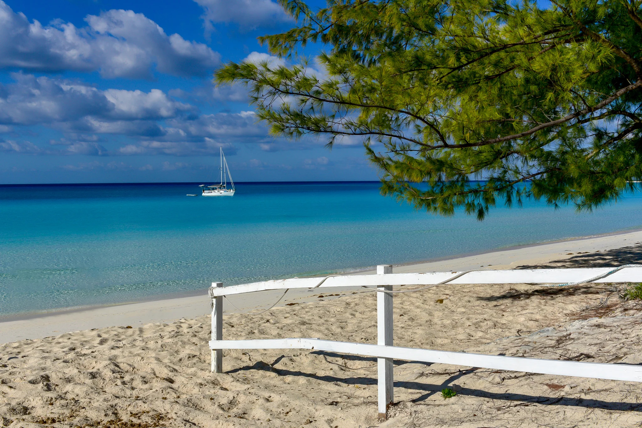 White timber fence following a quiet tropical beach beneath clouds