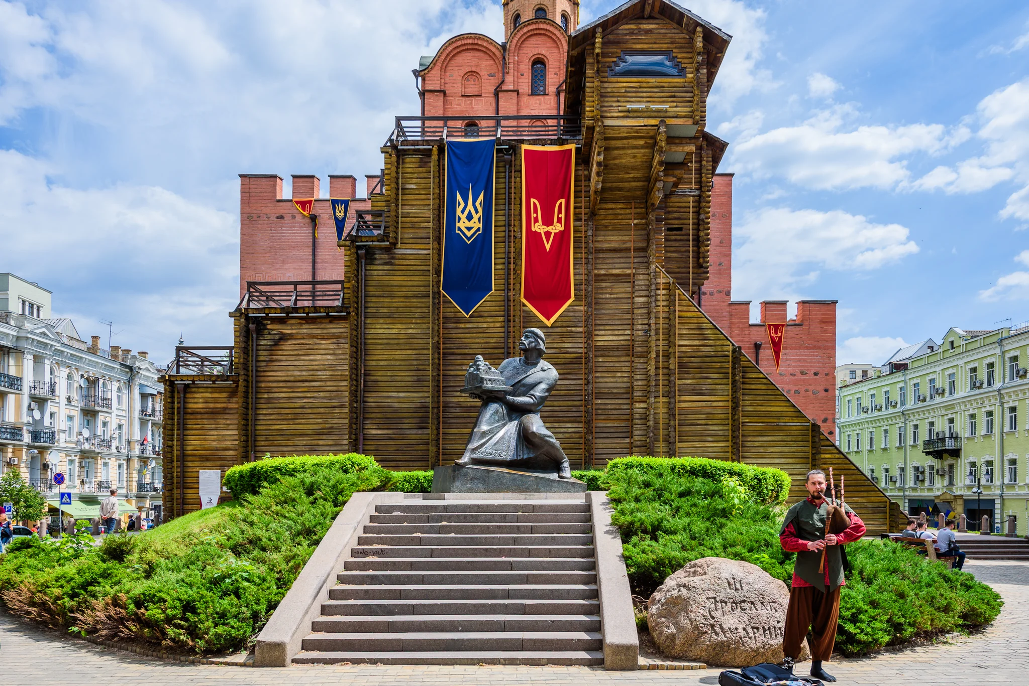 Tall wooden church facade and stone monument in a landscaped square