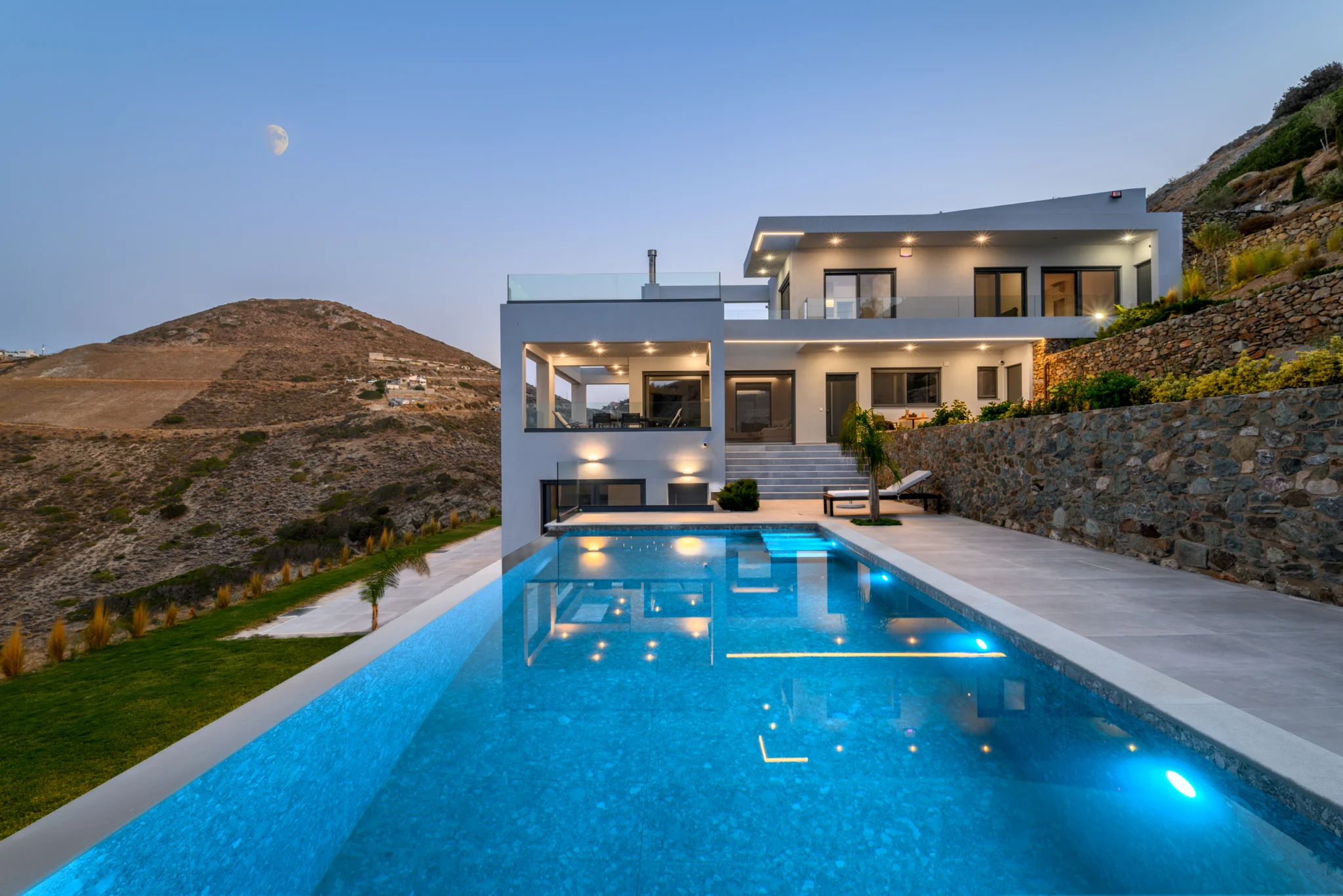 Illuminated swimming pool and white villa at twilight at Villa in Athens, Athens, Attica, Greece.