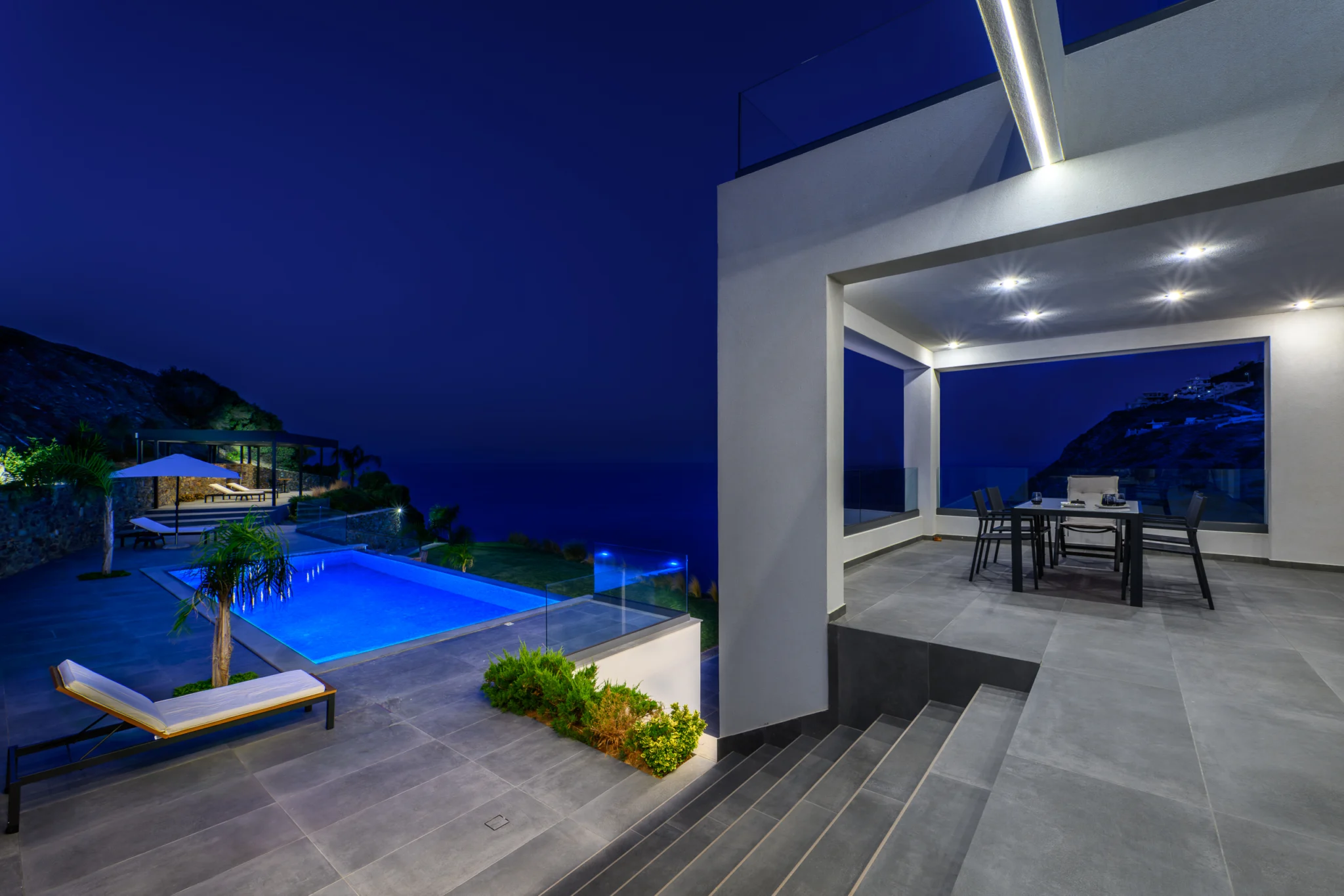 Covered outdoor dining area overlooking the illuminated pool at night at Villa in Athens, Athens, Attica, Greece.
