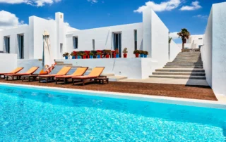 White architecture, orange sun loungers and a timber pool deck beside the swimming pool at Villa Edge in Paros.
