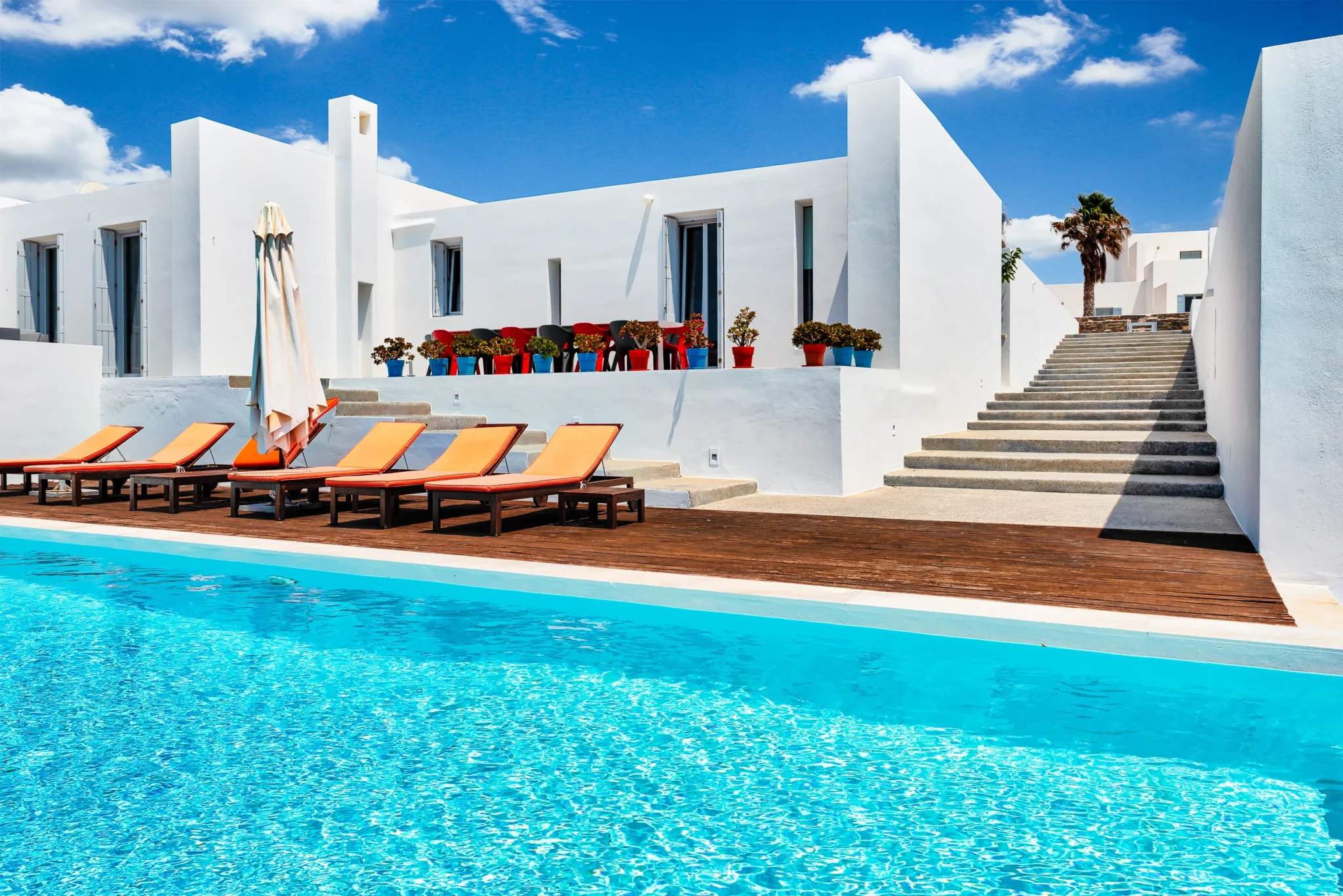 White architecture, orange sun loungers and a timber pool deck beside the swimming pool at Villa Edge in Paros.