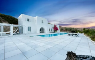 White villa and swimming pool beneath a pink and blue twilight sky at Villa Full Moon in Paros, Greece.