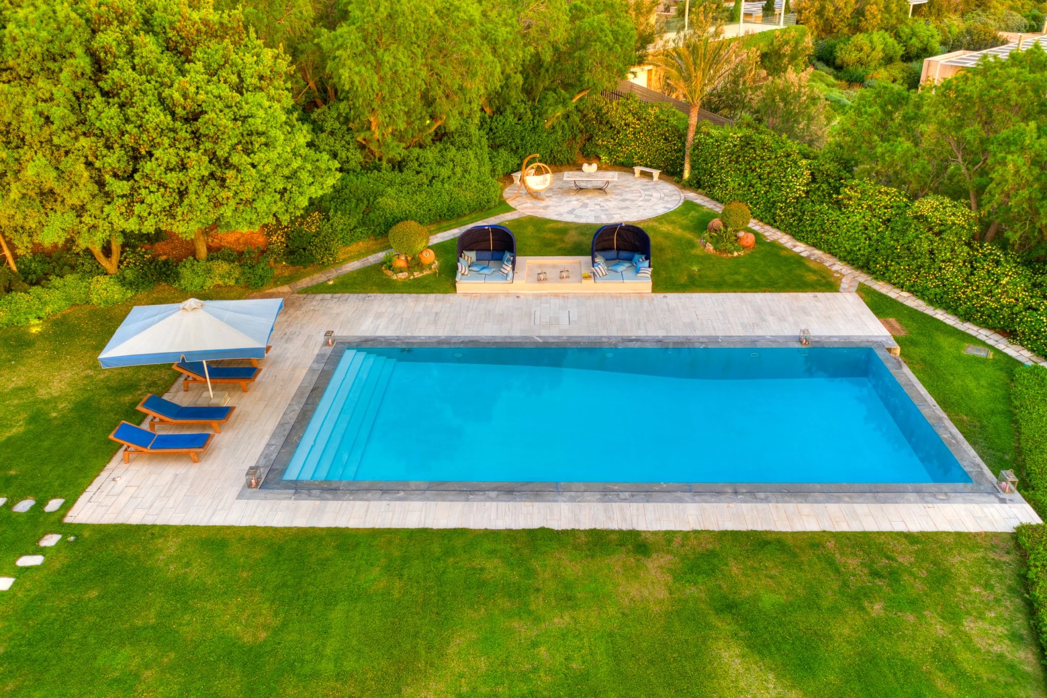 Swimming pool with sun loungers and garden seating at Villa Icarus.