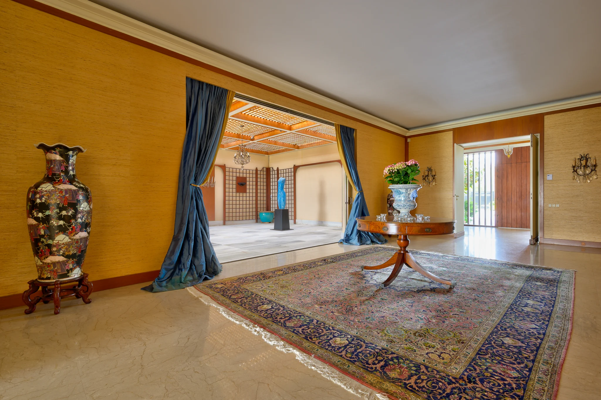Reception area with a round table, patterned rug and blue curtains at Villa Icarus.