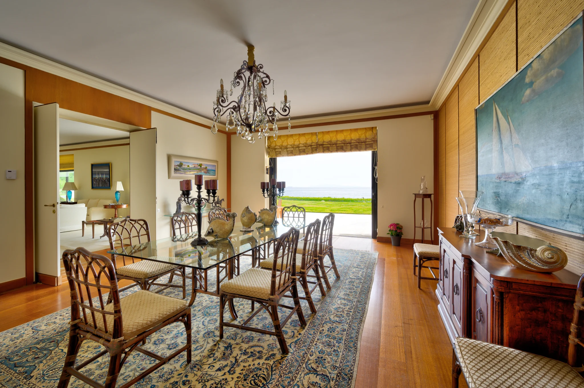 Dining room with a glass-topped table, chandelier and sea-facing doorway at Villa Icarus.