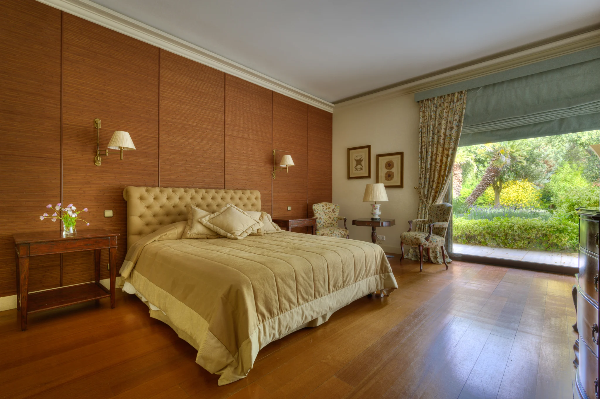 Bedroom with a tufted headboard, warm-toned wall panels and garden access at Villa Icarus.