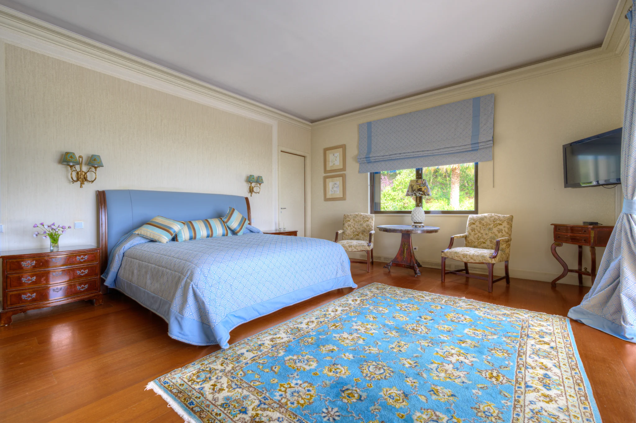 Bedroom with a blue headboard and bedspread, a patterned rug and timber flooring at Villa Icarus.