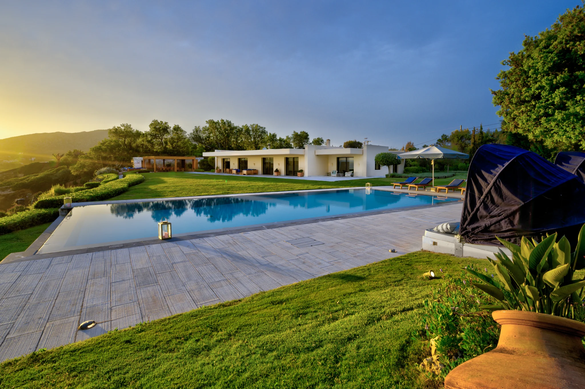 Swimming pool, lawn and villa in warm evening light at Villa Icarus.