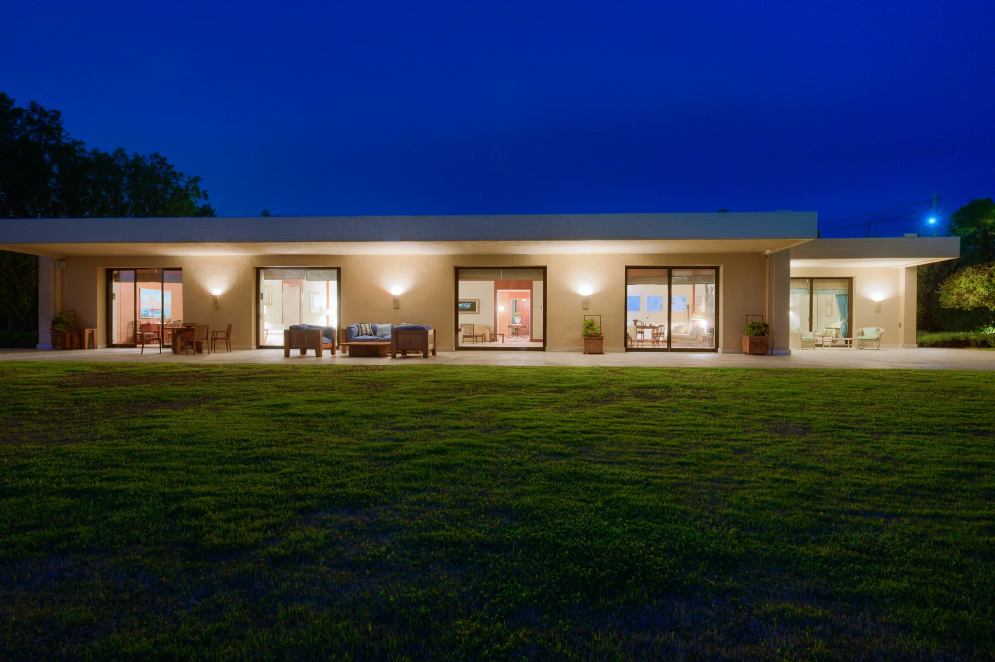 Illuminated villa facade seen across the lawn at night at Villa Icarus.