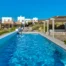 Blue swimming pool beside white and stone villa facades at Villa Olivia, Paros.