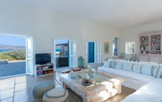 White sofa with striped cushions and turquoise doors framing the sea at Villa Salvia, Paros.
