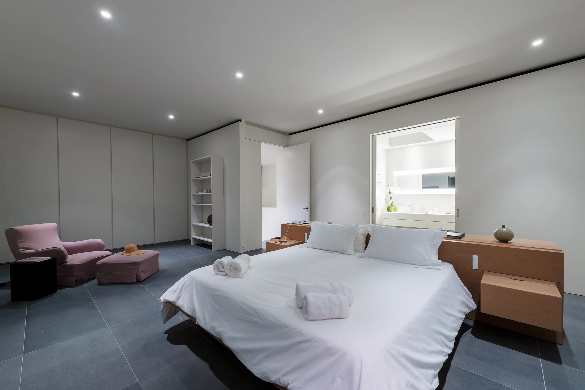 Bedroom at night with a white bed and mauve lounge chairs at Villa Seafront, Paros.