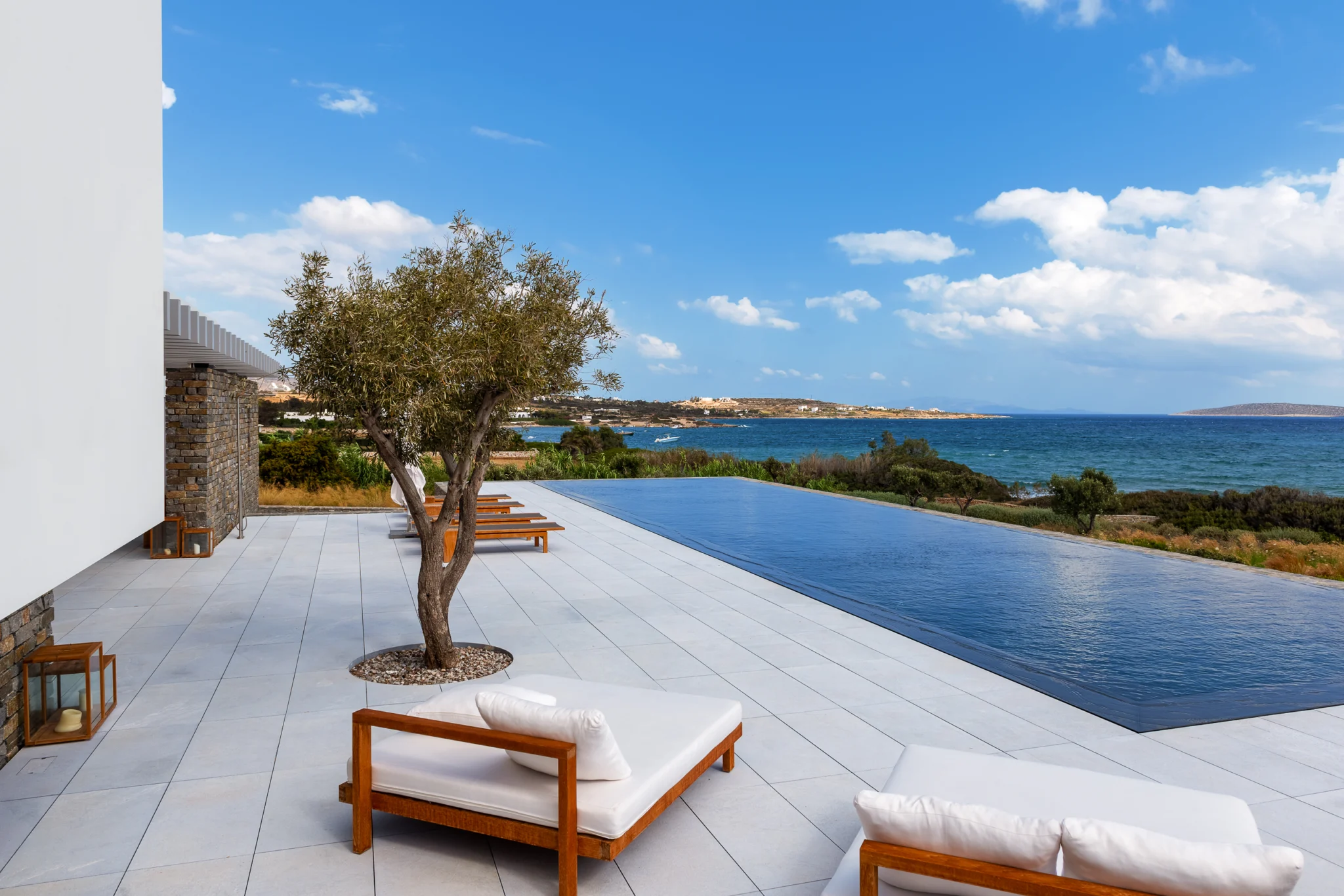 Infinity pool and timber loungers overlooking the sea at Villa Seafront, Paros.