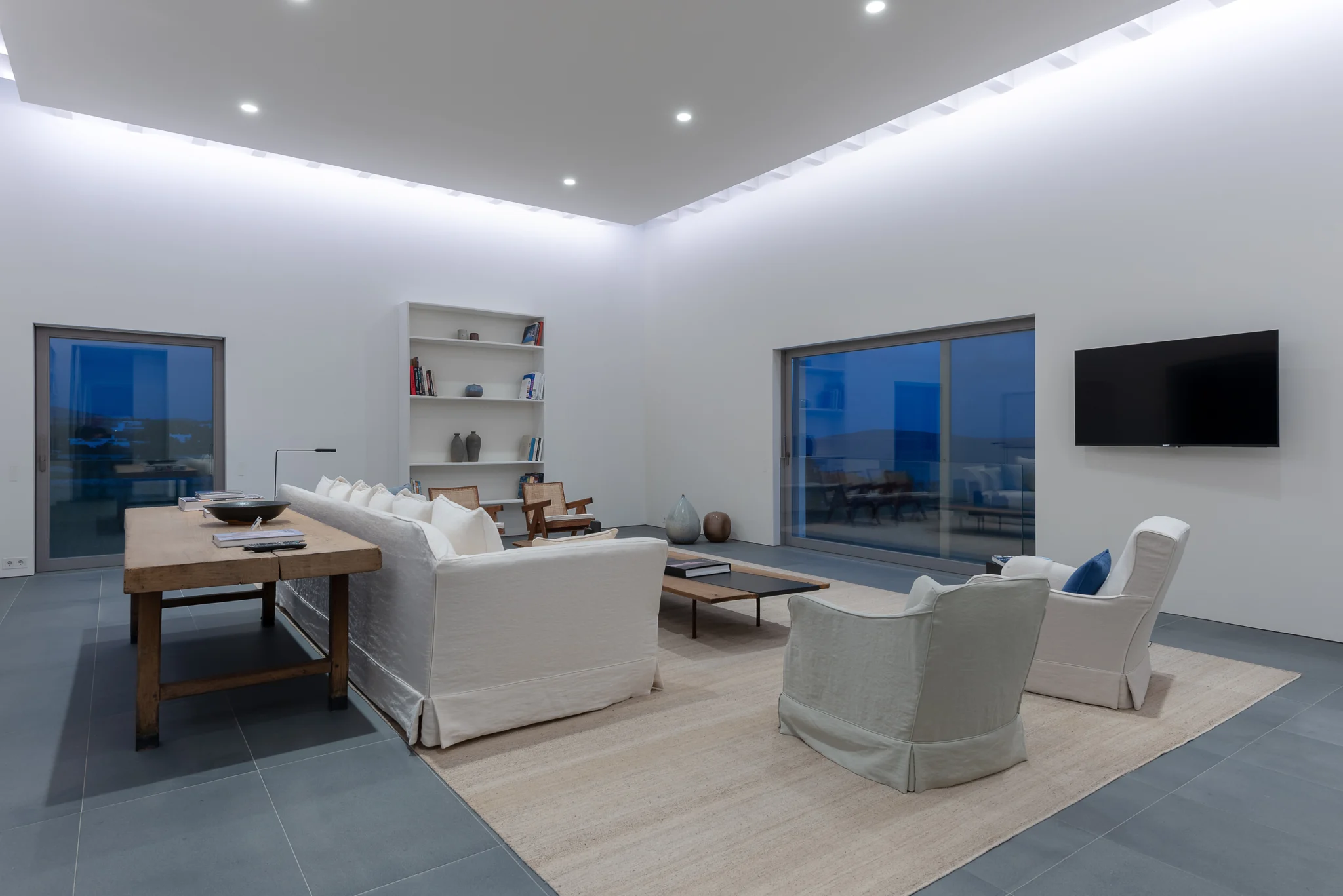 Living room at dusk with a sea view and illuminated ceiling at Villa Seafront, Paros.