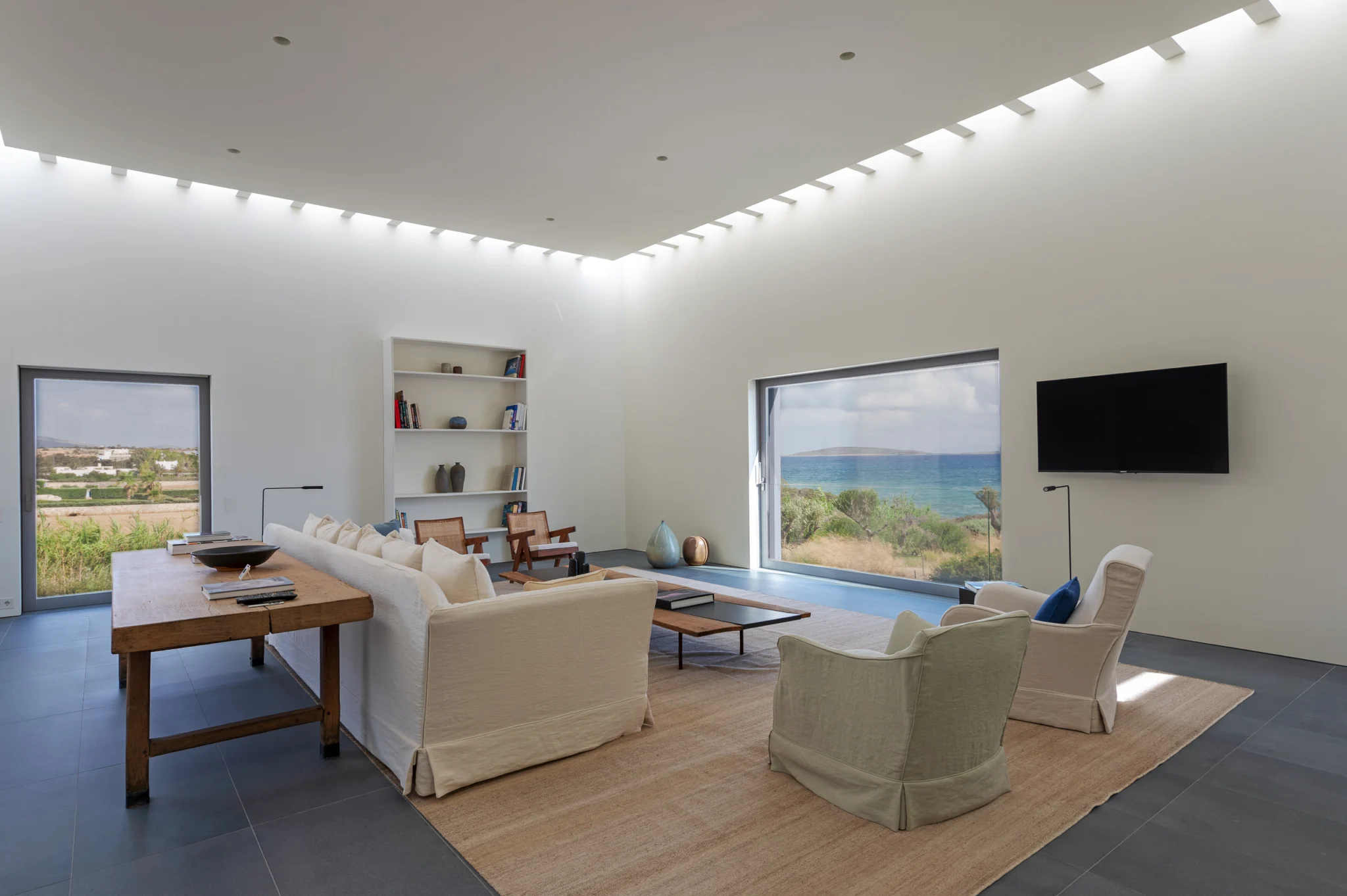 White living room with the sea framed by a large window at Villa Seafront, Paros.