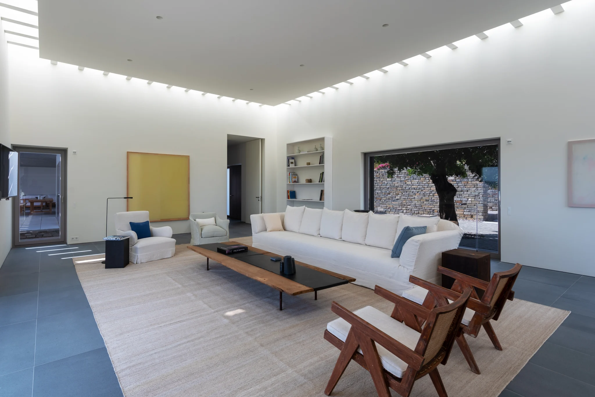 White sofa and timber furniture beneath a yellow artwork at Villa Seafront, Paros.