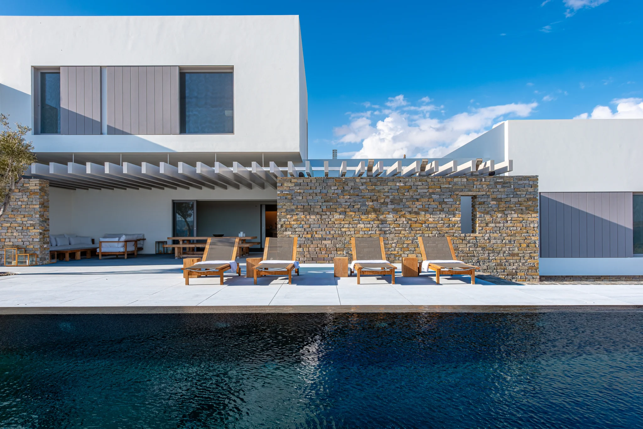 White and stone villa facade across the swimming pool at Villa Seafront, Paros.