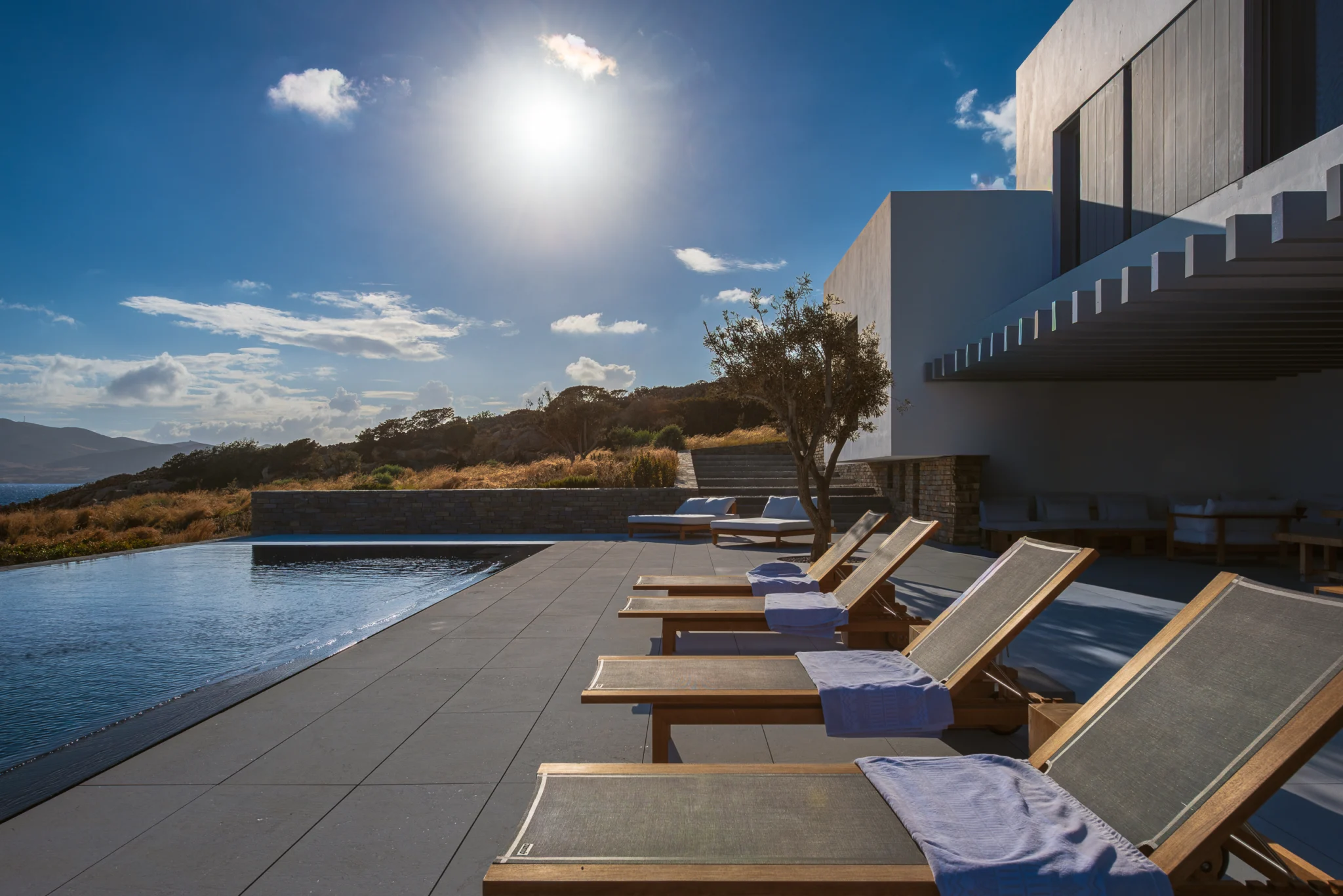 Timber loungers beside the pool in afternoon sunlight at Villa Seafront, Paros.
